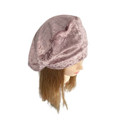Pink velvet headscarf on a mannequin head with brown hair against a white background