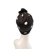 Black headscarf with white polka dots on a mannequin head against a white background