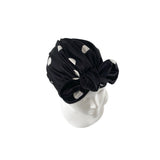 Black headscarf with white polka dots on a mannequin head against a white background