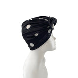 Black headscarf with white polka dots on a mannequin head against a white background