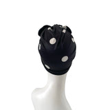 Black swim cap with white polka dots on a mannequin head against a white background