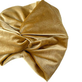 Gold velvet headband with a knot on a white background