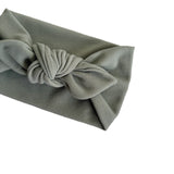 A sage green corduroy fabric headband with a knotted bow detail, shown on a plain white background.