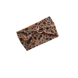A brown leopard print fabric headband with a knotted bow, featuring small multicolored spots, shown on a plain white background.