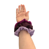 Hand wearing a purple scrunchie on a white background