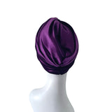 Purple satin turban on a white mannequin head against a white background