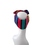 A multicolor striped fabric headband with a bow, displayed on a white mannequin head against a plain white background.