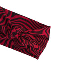 A close-up of a knotted fabric headband featuring a bold black and red wavy stripe pattern, shown against a plain white background.