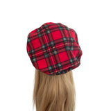 Red plaid beret on a mannequin head with long blonde hair against a white background