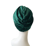 Green velvet turban on a mannequin head against a white background