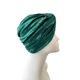 Green velvet turban on a mannequin head against a white background