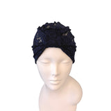 Navy blue headscarf with floral embellishments on a mannequin head against a white background