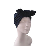 A black velvet turban headband with a large bow, displayed on a light gray mannequin head against a plain white background.