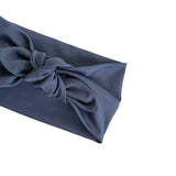 A dark slate blue fabric gift wrap or pouch with a knotted bow detail, shown on a plain white background.