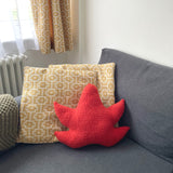 Gray sofa with patterned and red cushions in a room with curtains and radiator.