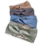 Stack of folded ribbed knit fabrics in beige, blue, and green on a white background
