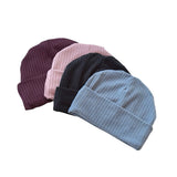 Four knit beanie hats in different colors on a white background