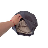Hand holding a gray fabric beanie against a white background