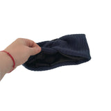 Hand holding a blue knitted headband against a white background