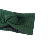 Green knitted headband with a bow on a white background