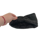 Hand holding a dark gray headband on a white background