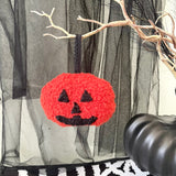 Halloween-themed decoration with a red jack-o'-lantern face on a sheer curtain background.