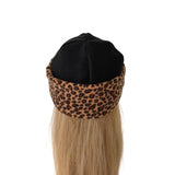 A black knit beanie with a brown and black leopard print fleece underband, shown on a mannequin head with long blonde hair against a white background.