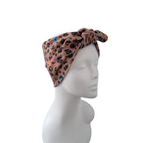 A leopard print knotted headwrap displayed on a white mannequin head against a plain white background.
