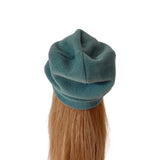 A teal blue-green fleece beret hat shown from the back, worn by a model with long light brown hair against a plain white background.