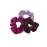 Three scrunchies in purple, pink, and brown on a white background