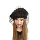 Black beret with a net veil on a mannequin head against a white background