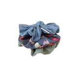Two scrunchies on a white background, one blue with a bow, the other floral.