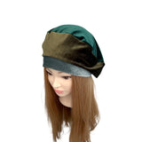 Mannequin head wearing a green and brown layered headscarf on a white background