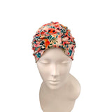 A multicolor floral turban hat displayed on a white mannequin head against a solid white background.