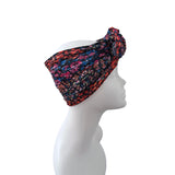 A multicolor patterned headwrap turban hat displayed on a white mannequin head against a plain white background.