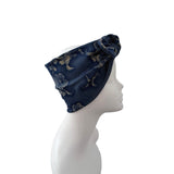 A dark navy blue fabric headband with a beige floral pattern, displayed on a white mannequin head in profile against a solid white background.
