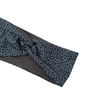 A close-up of a fabric headband with a blue and black leopard print pattern and a solid dark gray inner lining, shown on a plain white background.