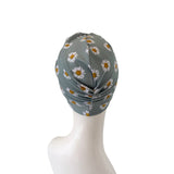 Gray headscarf with white daisy pattern on a mannequin head against a white background
