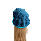 Blue hair towel draped over a person's head with long blonde hair on a white background