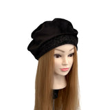 Black beret on a mannequin head with long brown hair against a white background