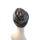 A metallic dark gray or gunmetal turban-style headpiece displayed on a white mannequin head against a plain white background.