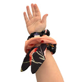 Hand wearing a floral scrunchie on a white background