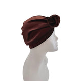 Brown turban with a decorative bow on a mannequin head against a white background