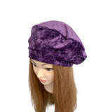 Purple velvet beret on a mannequin head with brown hair against a white background