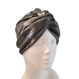 A metallic bronze turban hat displayed on a white mannequin head against a plain white background.