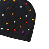 A close-up of a black beanie hat embellished with scattered small rhinestones in red, orange, white, and purple, set against a plain white background.