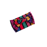 A multicolor striped fabric headband with a knotted bow center, shown on a plain white background.
