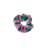 Pink scrunchie with green leaf pattern on a white background