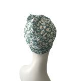 Green and white patterned headscarf on a mannequin head against a white background