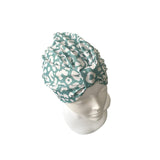 Teal headscarf with white pattern on a mannequin head against a white background